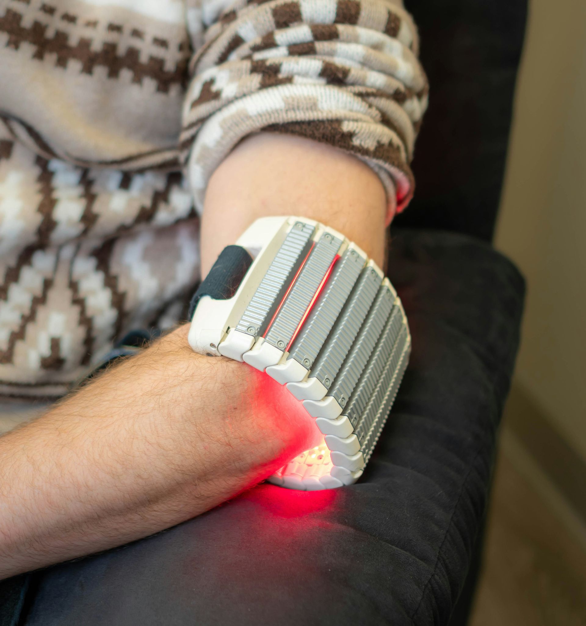 Person with red light therapy device on arm